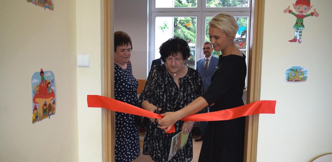 Dyrektor żłobka przecina wstęgę trzymana przez Zastępcę Burmistrza