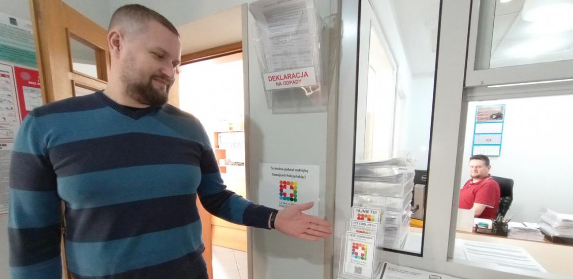 Pracownik Urzędu Miejskiego w Połczynie-Zdroju Mateusz Owczarek prezentuje nowe naklejki